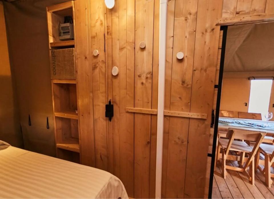 Interno rustico in legno con letto e zona pranzo, illuminazione calda e accogliente.