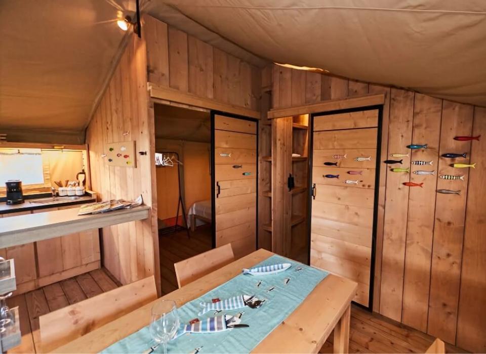Interno di una cabina in legno con decorazioni a forma di pesce e cucina.