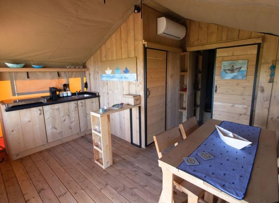 Interno rustico con cucina in legno, tavolo da pranzo e decorazioni nautiche.