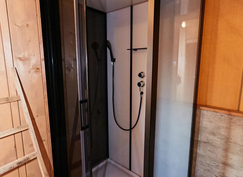 Cabina doccia moderna con porta a vetro e doccia a soffione.