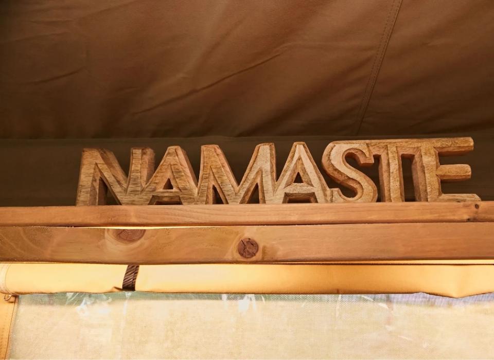 Scritta 'NAMASTE' in legno su una mensola, atmosfera accogliente e rustica.