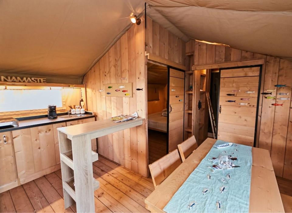 Interno accogliente in legno con tavolo da pranzo e decorazioni colorate a forma di pesce.