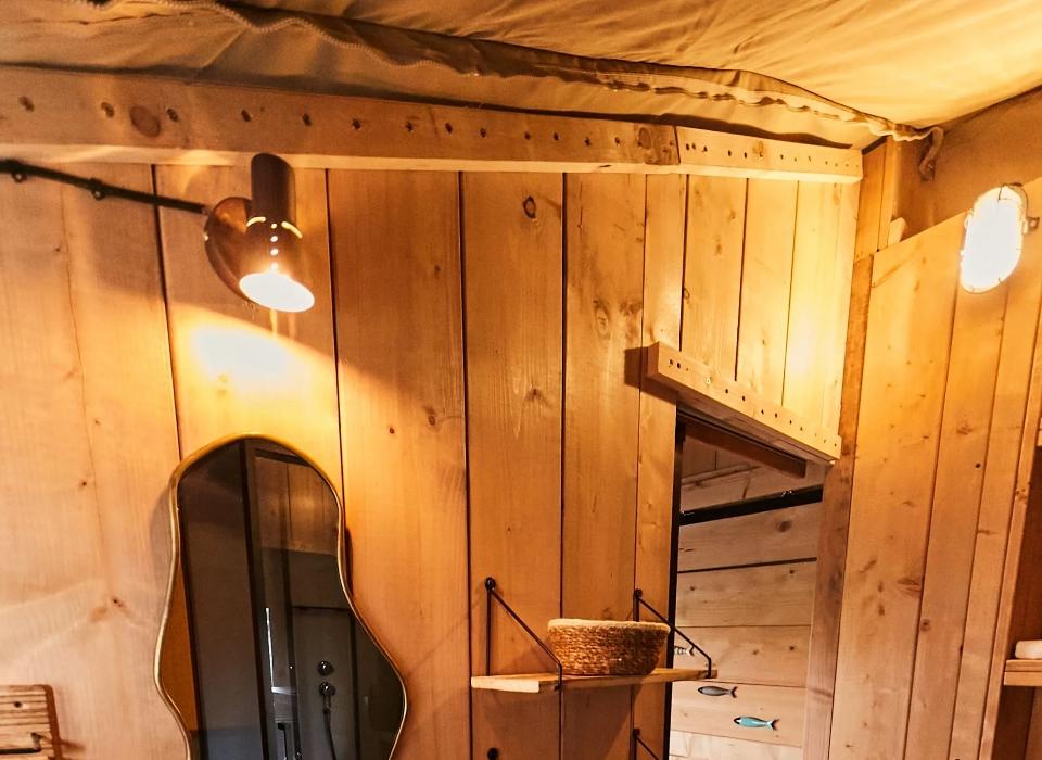 Bagno rustico con lavandino bianco, specchio decorativo e scaffali in legno.