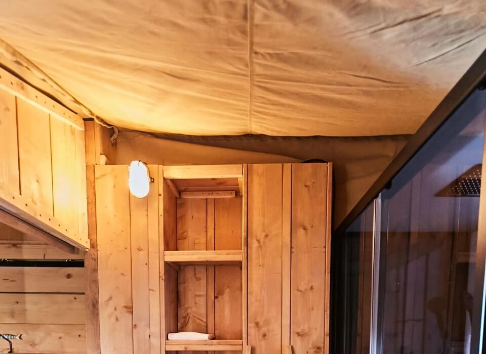 Interno in legno con scaffali, scala e luce soffusa, stile rustico e accogliente.