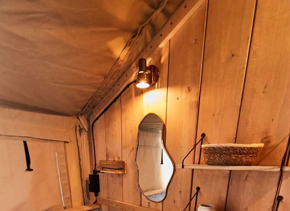 Bagno rustico con lavandino in legno, specchio e cestini intrecciati.