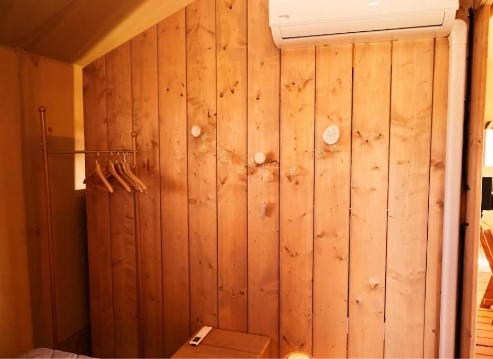 Interno in legno con appendiabiti, condizionatore e illuminazione a stringa.