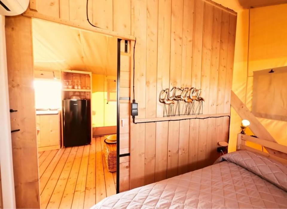 Interno accogliente con pareti in legno, letto e cucina a vista.