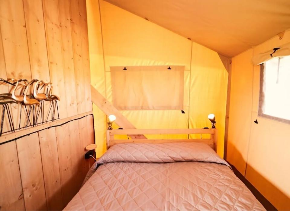 Camera da letto in tenda con pareti in legno e decorazioni metalliche.
