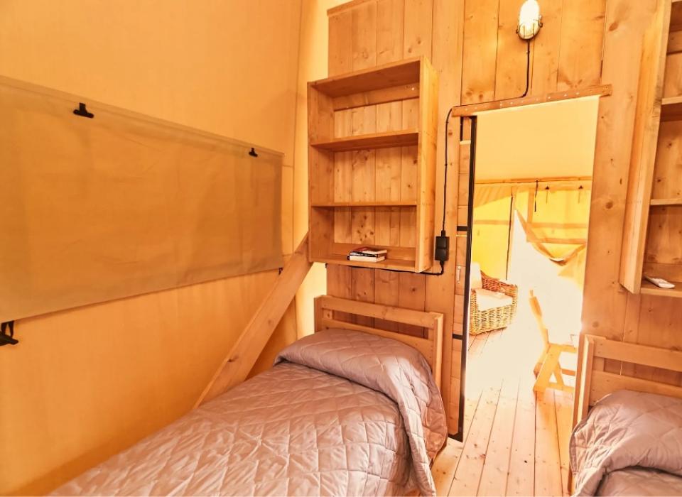 Camera in legno con due letti singoli e scaffali, luminoso e accogliente.