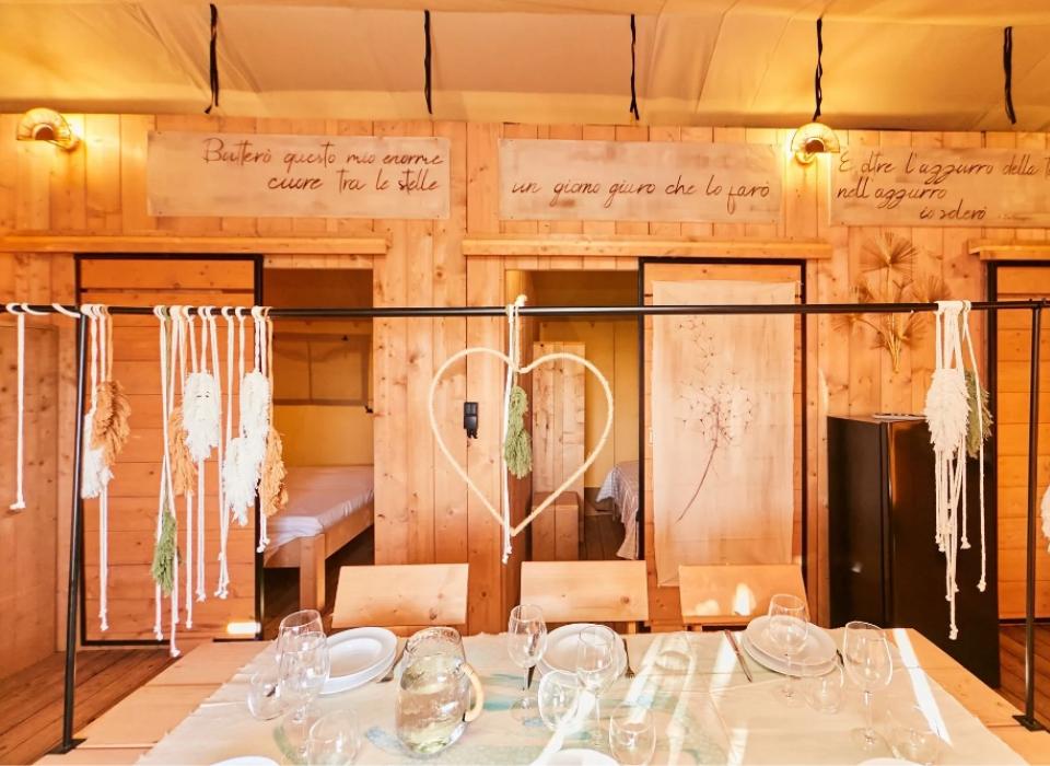 Interno in legno con tavolo apparecchiato, decorazioni e scritte sulle pareti.