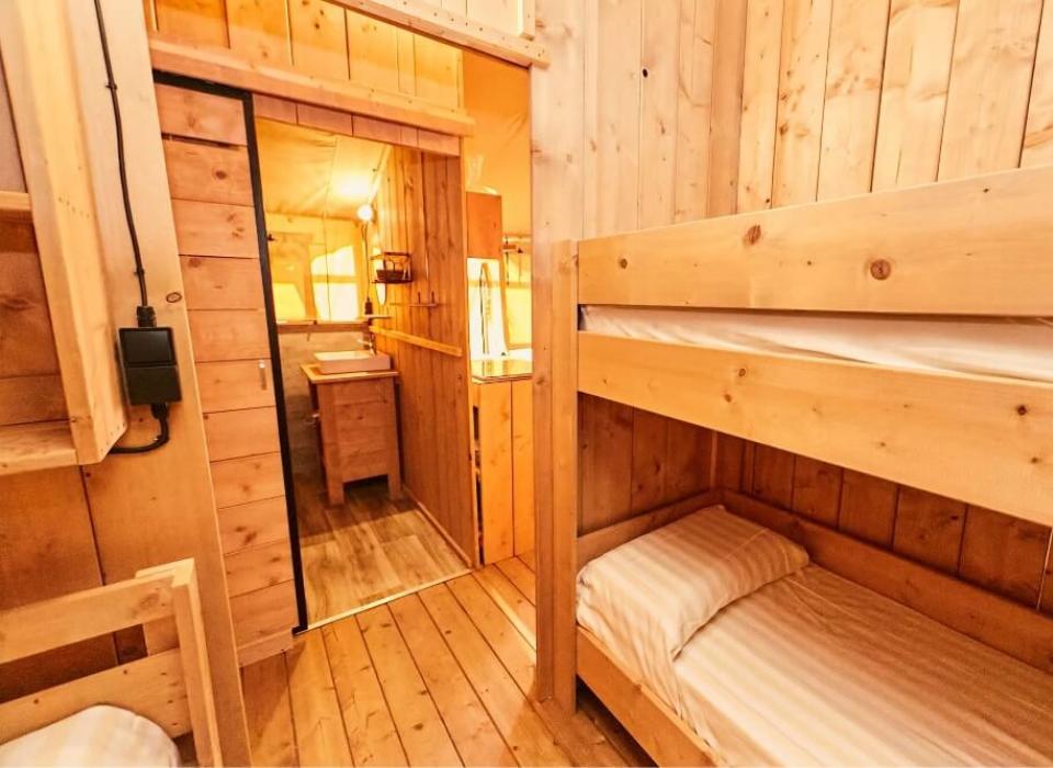 Interno di una cabina in legno con letti a castello e bagno.