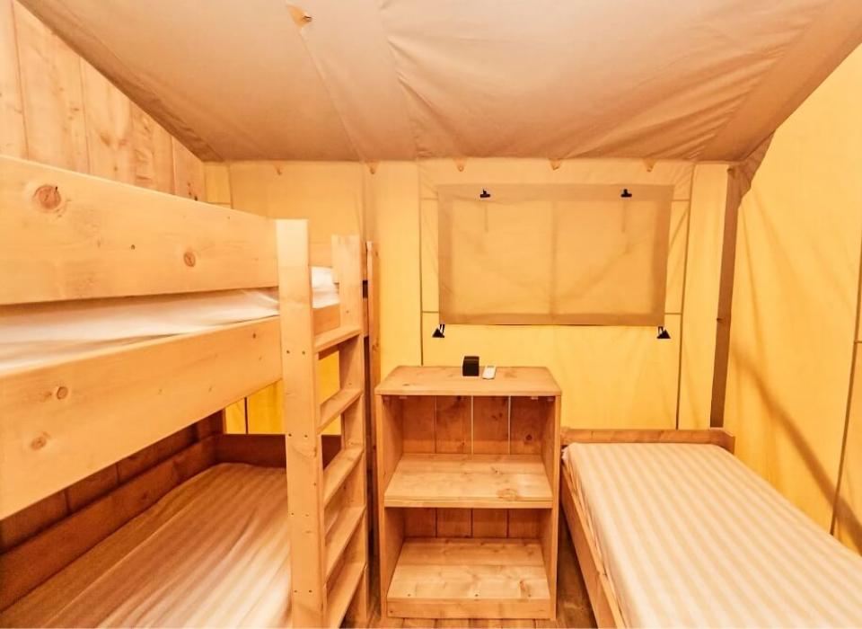 Interno di una tenda con letti a castello e mobili in legno.