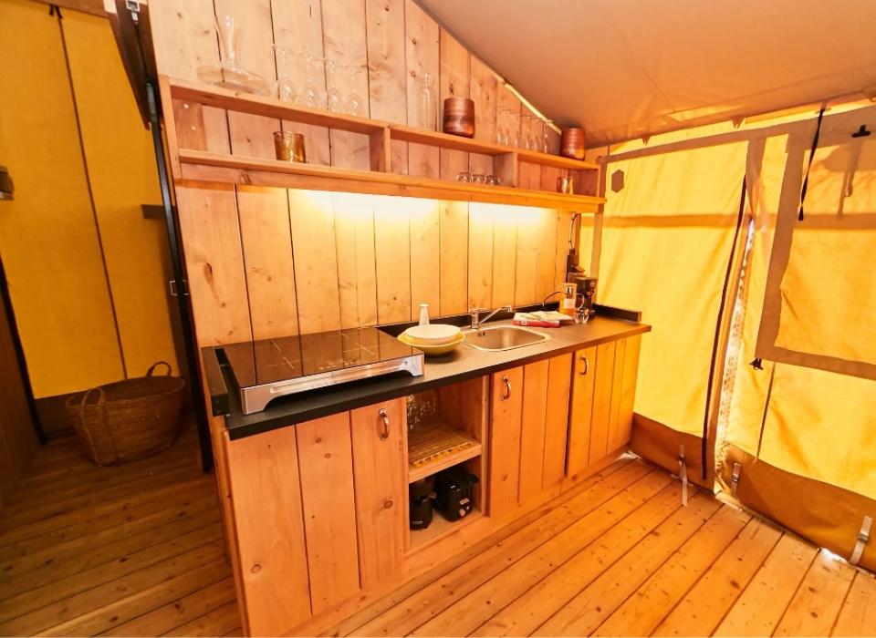 Cucina in legno in una tenda, con piano cottura e lavello.