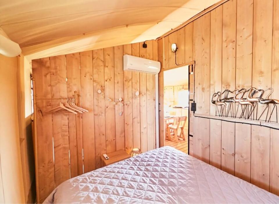 Camera in legno con letto, condizionatore e decorazioni a forma di uccelli.