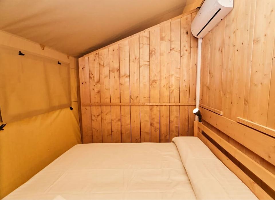 Camera con pareti in legno, letto matrimoniale e condizionatore d'aria.