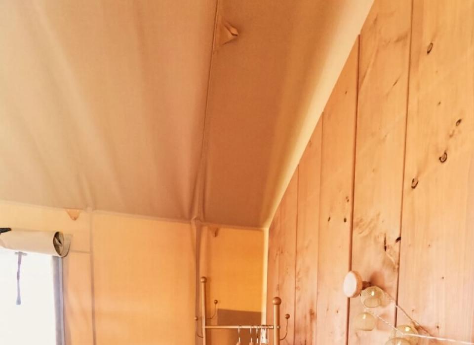 Interno di una stanza con pareti di legno e un appendiabiti con grucce.